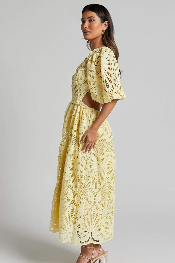 Woman in yellow lace maxi dress with puff sleeves and cut-out waist.