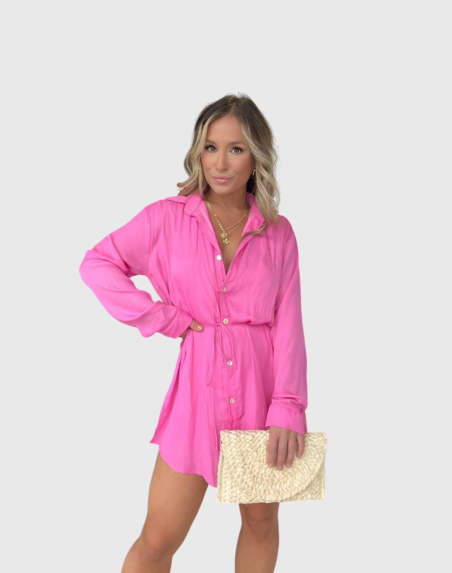 Pink - A woman wearing a long-sleeve burgundy satin romper with a button-down front, pointed collar, and cinched waist, styled with knee-high beige boots.