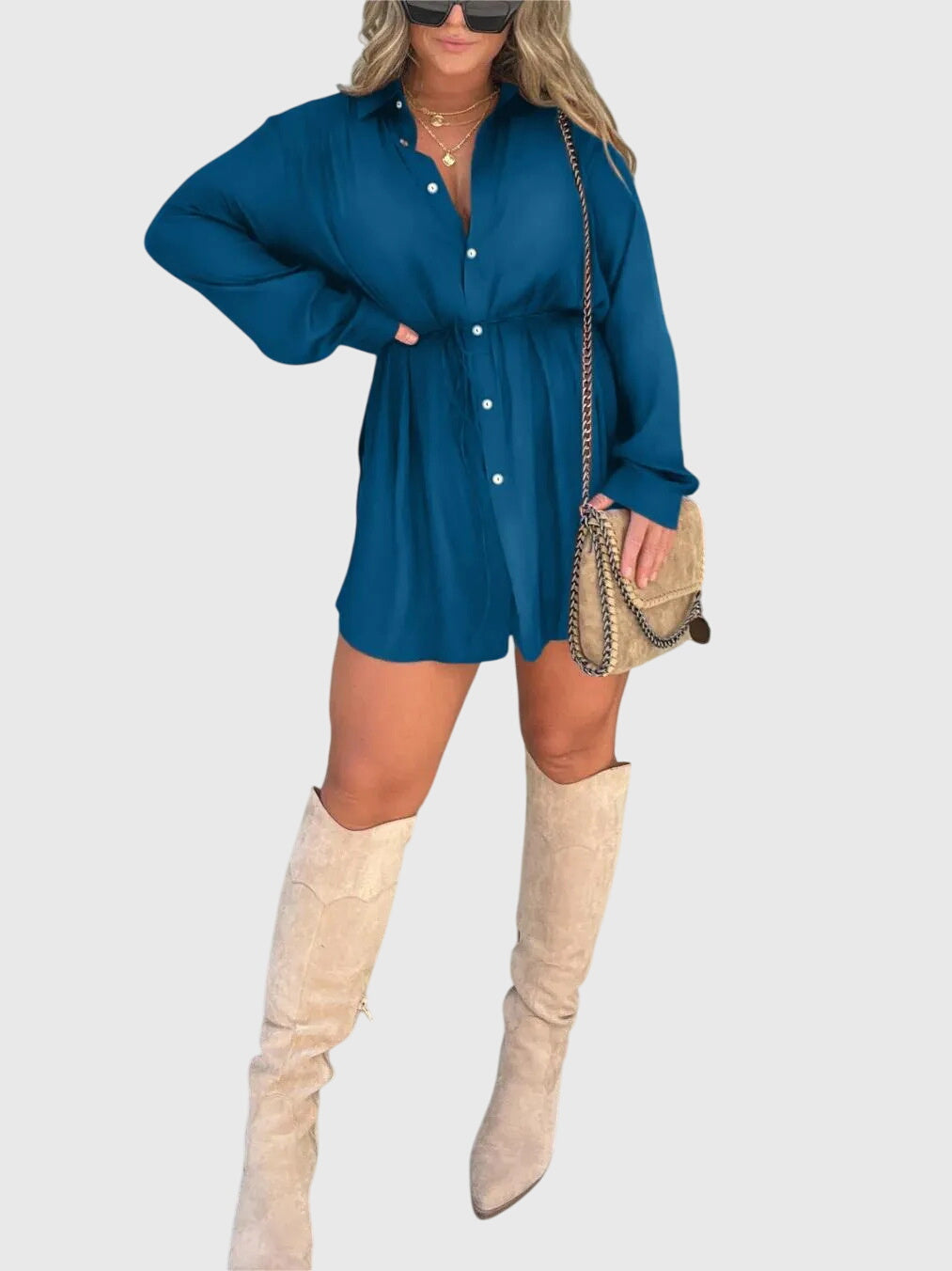Blue - A woman wearing a long-sleeve burgundy satin romper with a button-down front, pointed collar, and cinched waist, styled with knee-high beige boots.