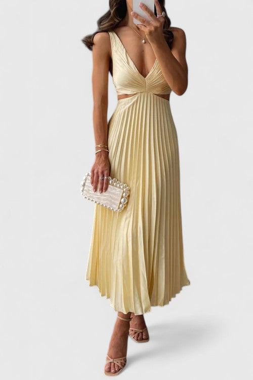 A woman wearing a pale yellow pleated satin midi dress with a plunging V-neckline and side waist cutouts, holding a pearl-embellished clutch.