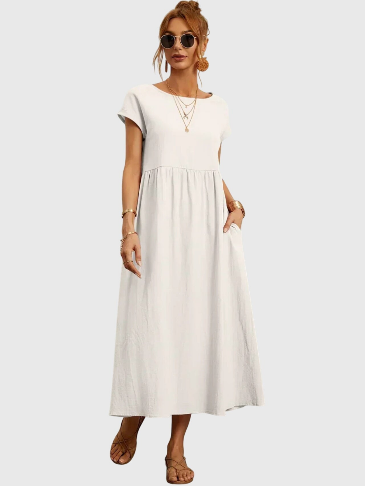 White - Woman wearing a solid short sleeve babydoll maxi dress with a gathered waist and hands resting in side pockets.