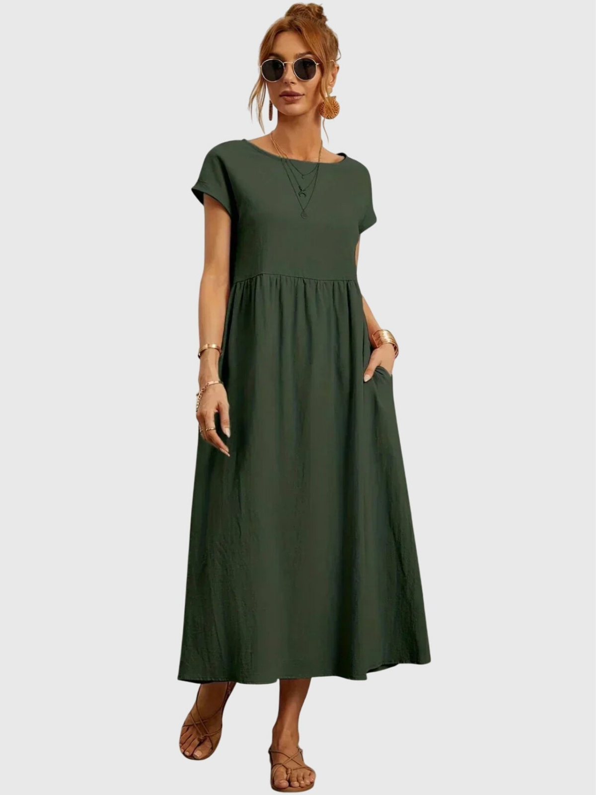 Army Green - Woman wearing a solid short sleeve babydoll maxi dress with a gathered waist and hands resting in side pockets.