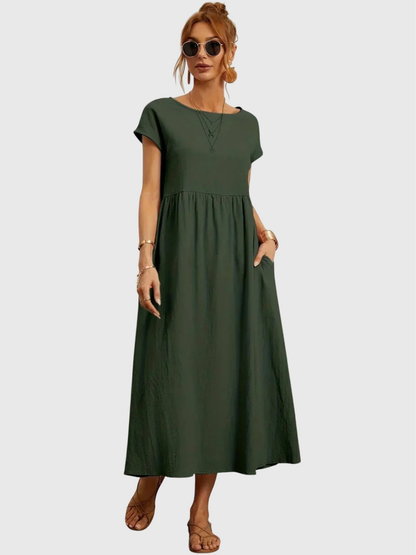 Army Green - Woman wearing a solid short sleeve babydoll maxi dress with a gathered waist and hands resting in side pockets.