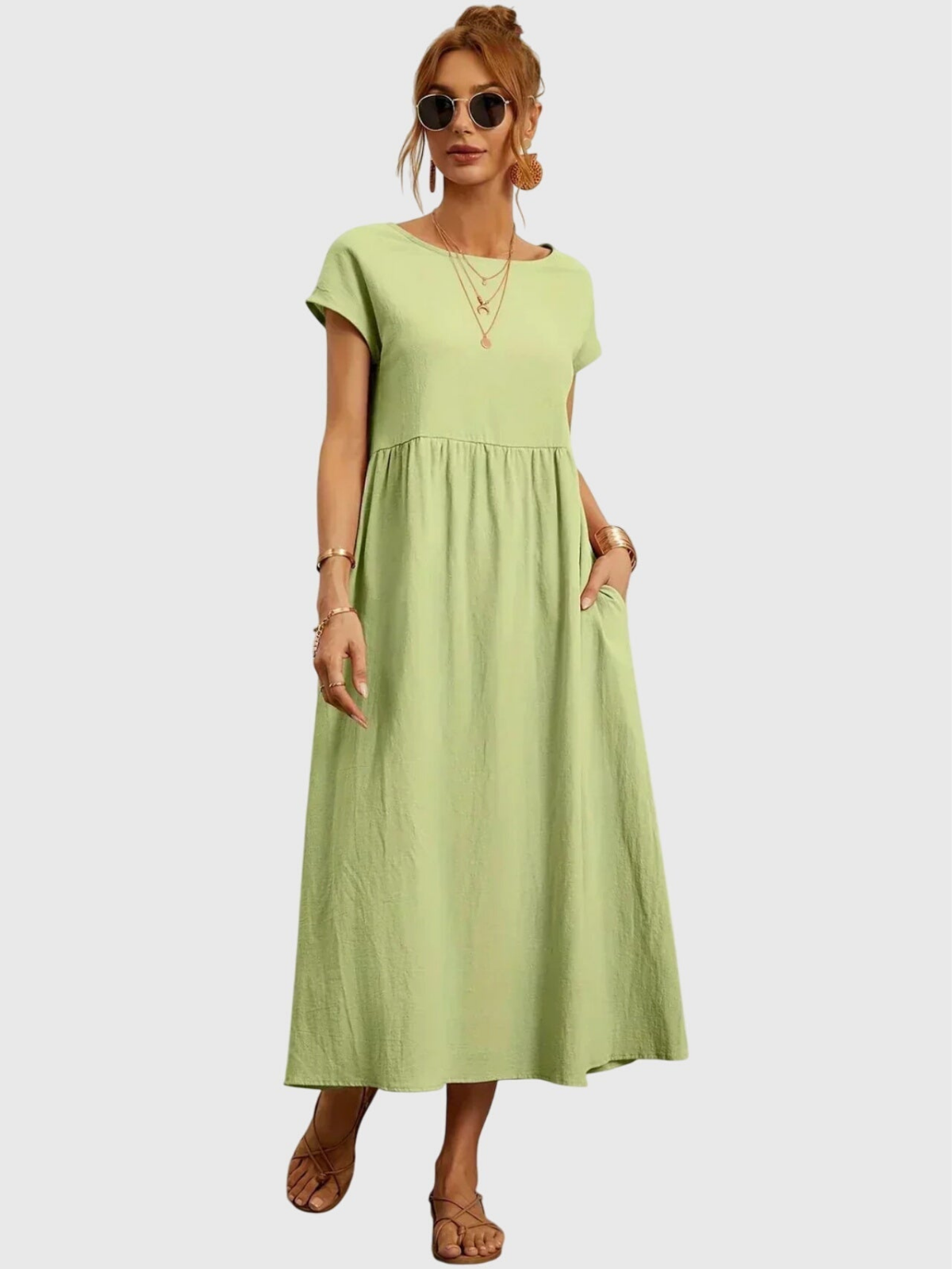 Light Green - Woman wearing a solid short sleeve babydoll maxi dress with a gathered waist and hands resting in side pockets.