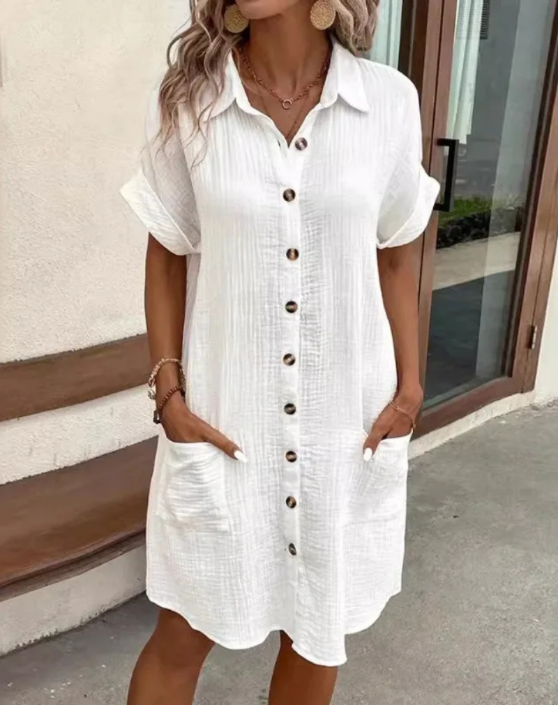 White - Woman wearing a lightweight, textured short-sleeve button-front mini shirt dress with two large front patch pockets.