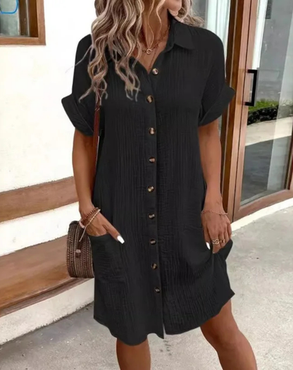 Black - Woman wearing a lightweight, textured short-sleeve button-front mini shirt dress with two large front patch pockets.