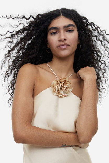 Woman in cream satin halter dress with floral detail