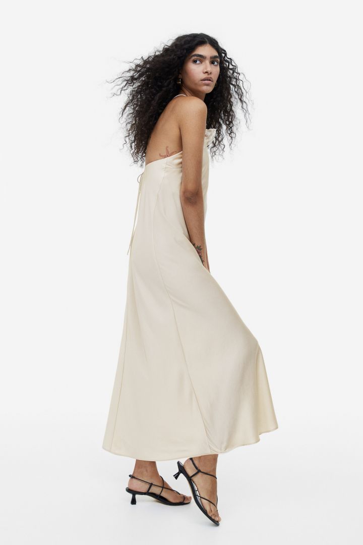 Woman in cream satin halter dress with floral detail