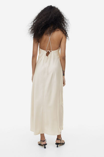 Woman in cream satin halter dress with floral detail