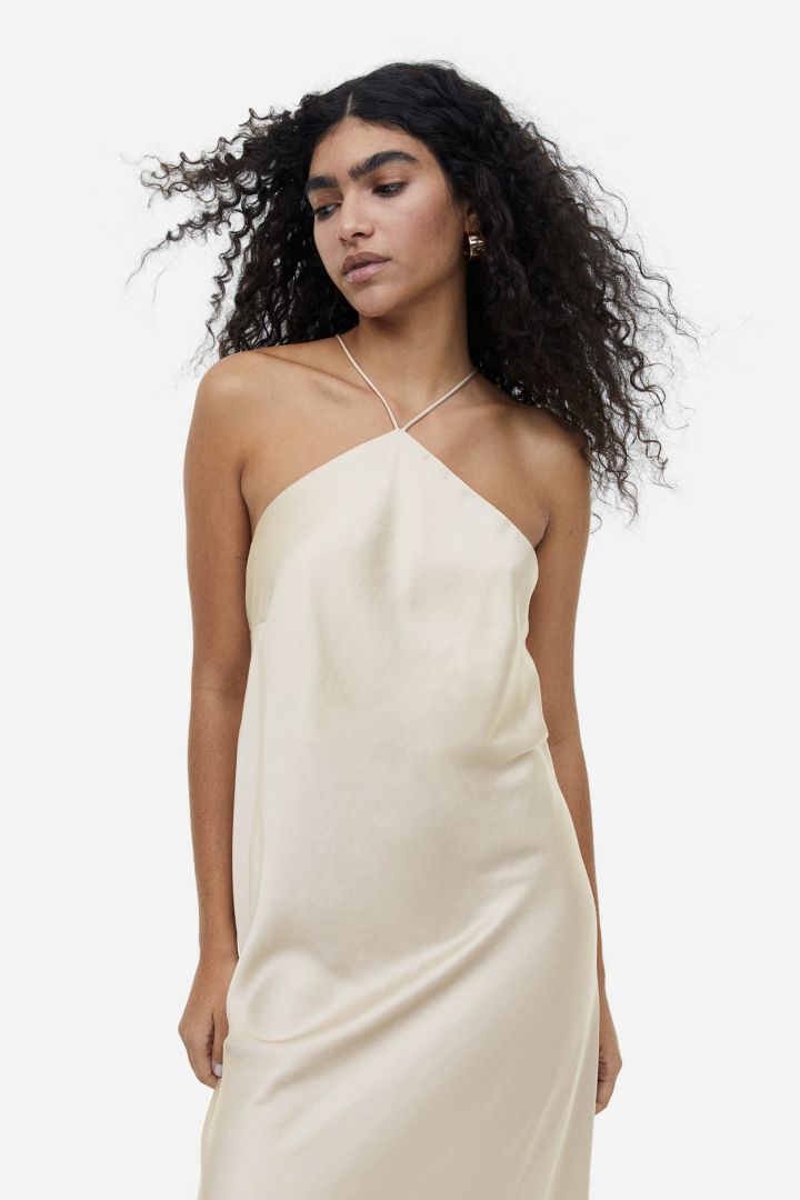 Woman in cream satin halter dress with floral detail