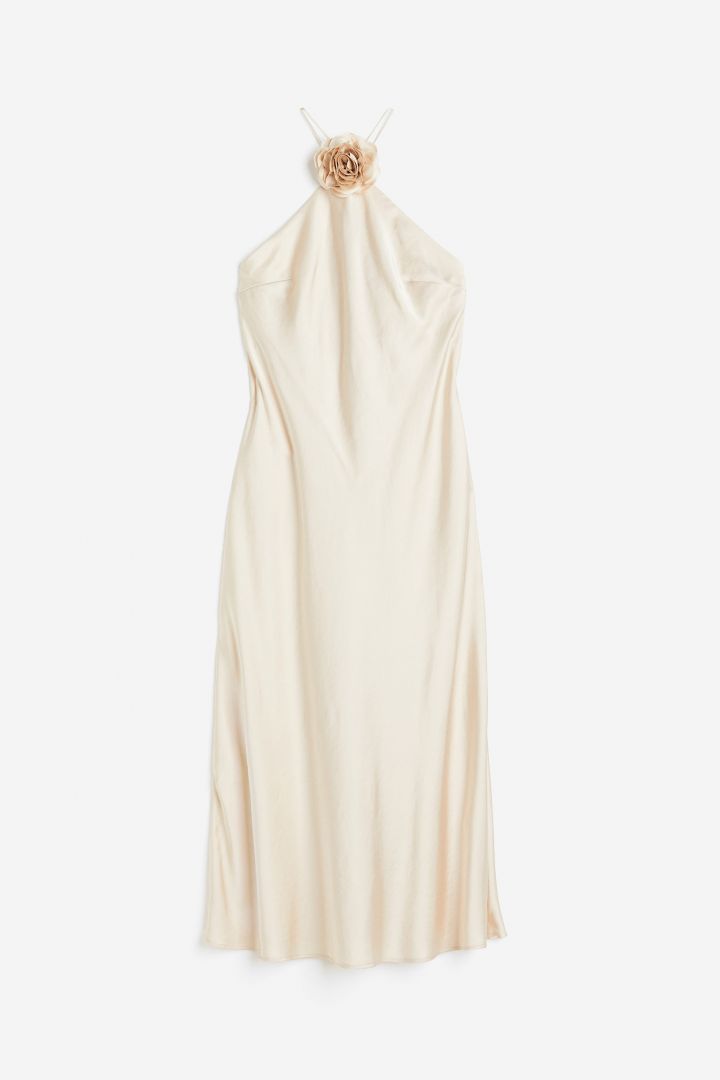 Woman in cream satin halter dress with floral detail