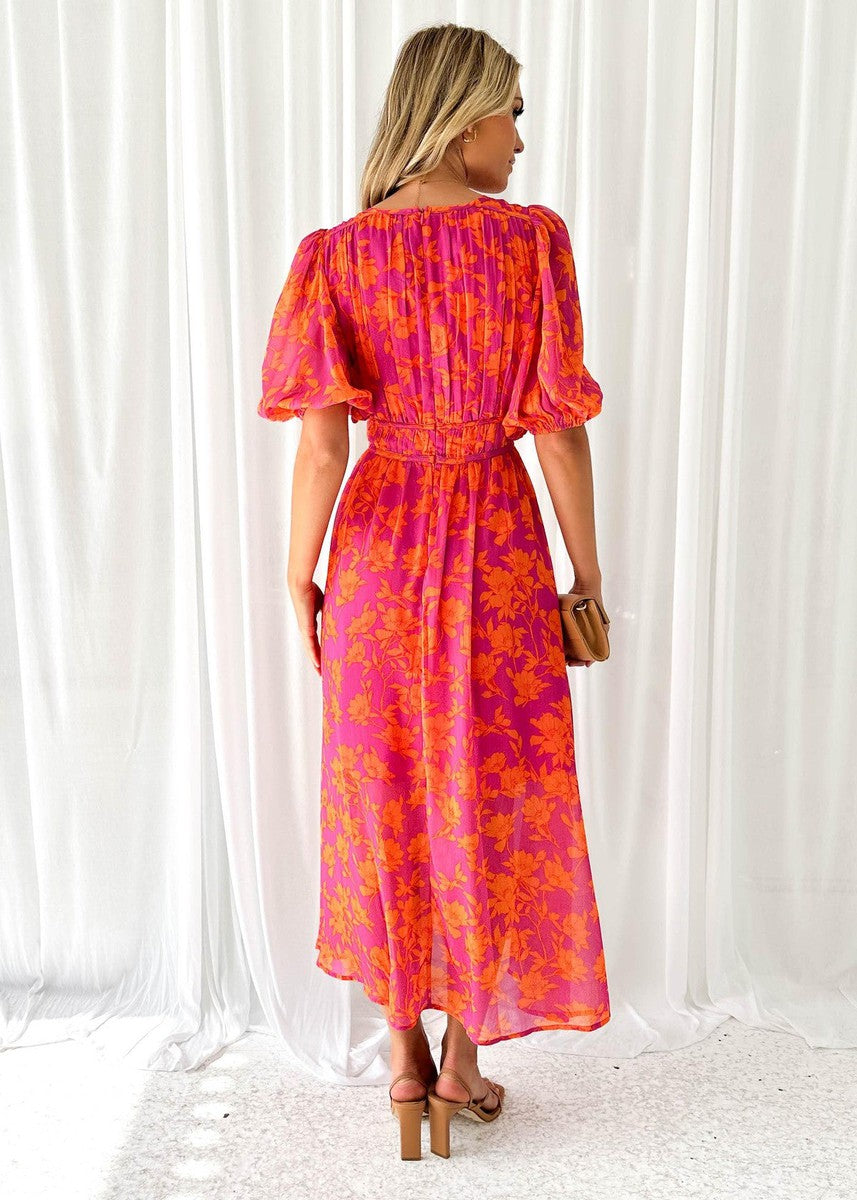 Orange - A woman smiling in a vibrant pink and orange floral print chiffon maxi dress with a deep V-neckline, short puff sleeves, and a smocked waist.