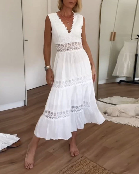 A woman wearing a sleeveless white cotton midi dress with a scalloped V-neckline, sheer eyelet lace waist insert, and a tiered skirt with lace paneling.