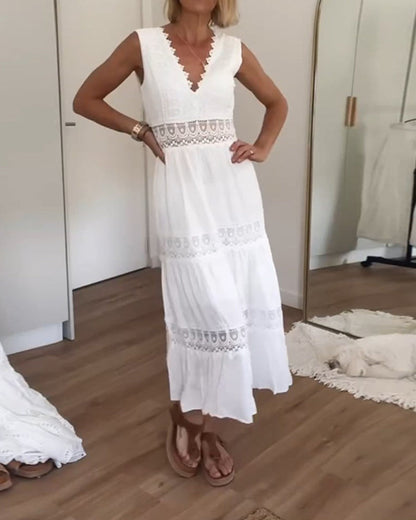 White - A woman wearing a sleeveless white cotton midi dress with a scalloped V-neckline, sheer eyelet lace waist insert, and a tiered skirt with lace paneling.