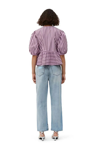 Woman in pink and brown striped blouse and khaki shorts holding sunglasses