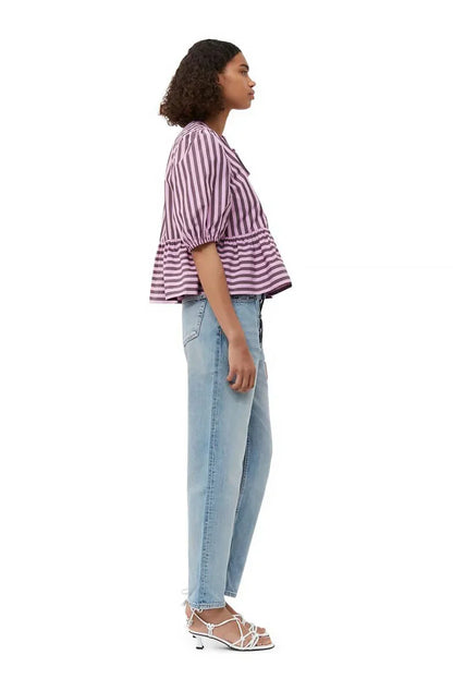Woman in pink and brown striped blouse and khaki shorts holding sunglasses