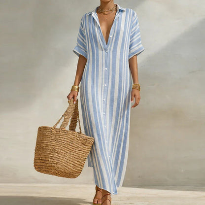 Sky Blue - Woman walking outdoors wearing a long, striped, short-sleeve button-front maxi dress and carrying a woven straw tote bag.