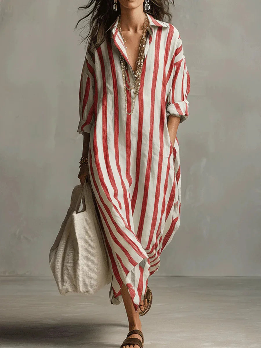 Red - A woman walks wearing an oversized, vertical-striped linen maxi dress in navy and white, featuring a collared V-neck, rolled-up sleeves, and side pockets, paired with a woven tote bag.
