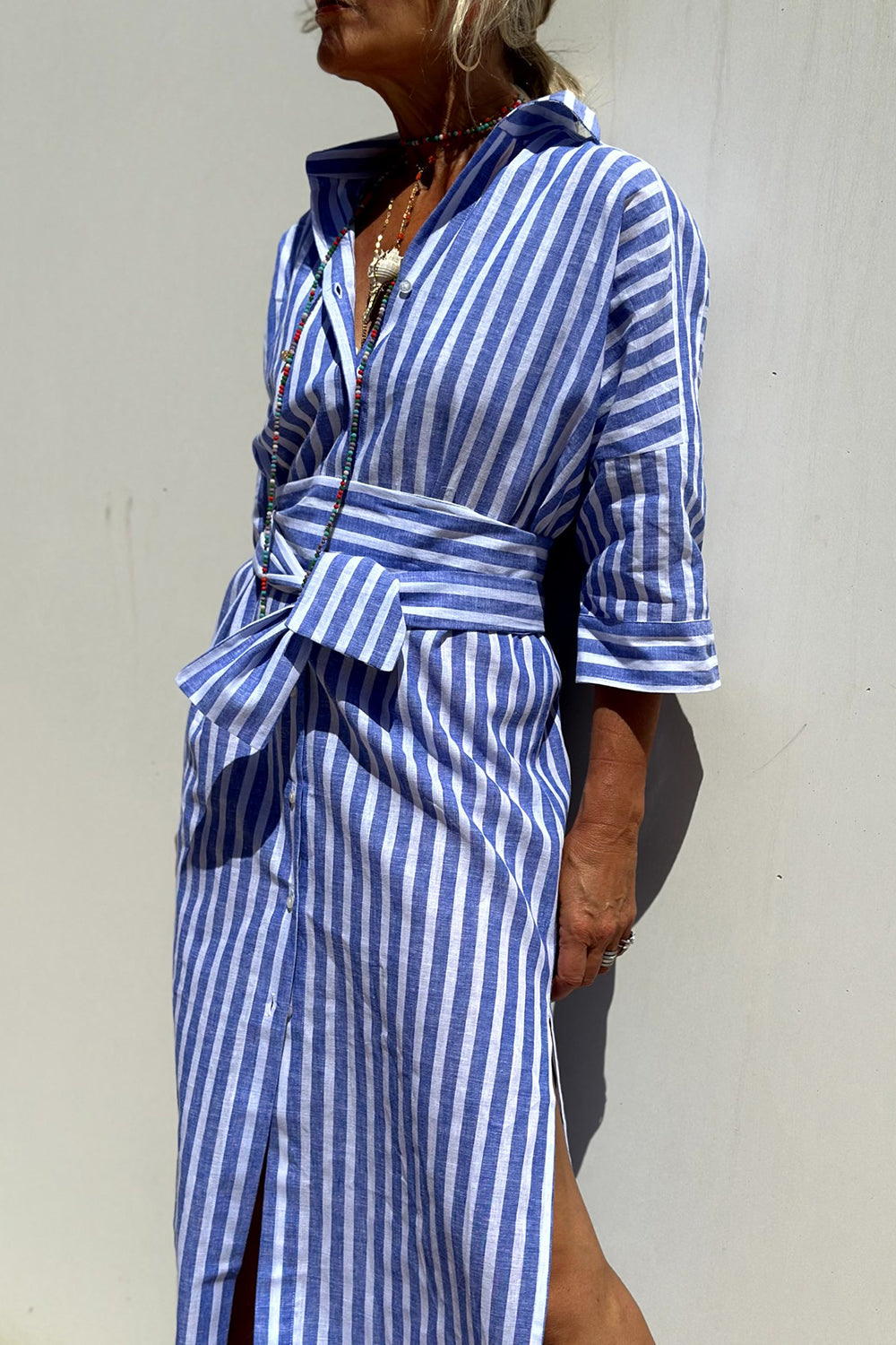 Pink - Woman walking outdoors wearing a striped poplin button-front midi dress with a collar and 3/4 sleeves, carrying a woven straw tote bag.