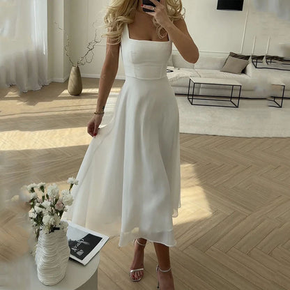 White - A woman wearing a solid white midi dress with a structured square-neck corset bodice and a flowy chiffon A-line skirt, paired with silver heeled sandals.