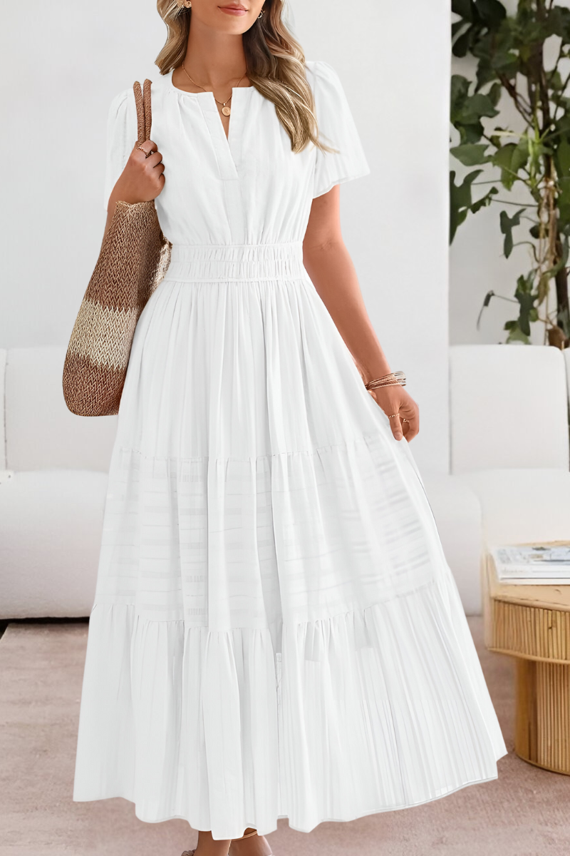 White - A woman wearing a yellow textured cotton maxi sundress featuring a smocked waist, flutter sleeves, and a tiered skirt, carrying a woven straw tote bag.