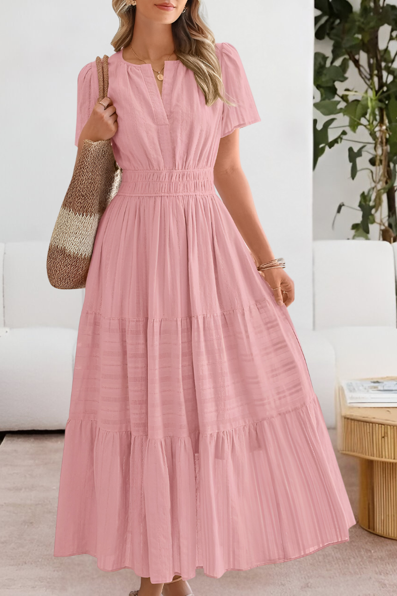 Pink - A woman wearing a yellow textured cotton maxi sundress featuring a smocked waist, flutter sleeves, and a tiered skirt, carrying a woven straw tote bag.