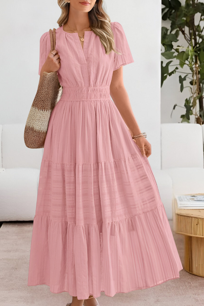Pink - A woman wearing a yellow textured cotton maxi sundress featuring a smocked waist, flutter sleeves, and a tiered skirt, carrying a woven straw tote bag.