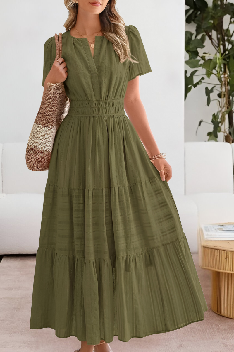 Green - A woman wearing a yellow textured cotton maxi sundress featuring a smocked waist, flutter sleeves, and a tiered skirt, carrying a woven straw tote bag.