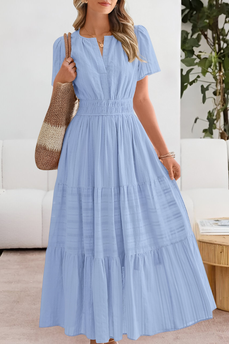 Blue - A woman wearing a yellow textured cotton maxi sundress featuring a smocked waist, flutter sleeves, and a tiered skirt, carrying a woven straw tote bag.