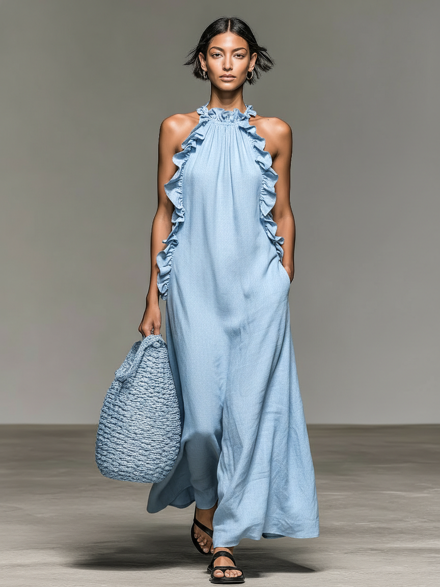 Light Blue - Model walking in a sleeveless, textured maxi dress with a ruffled halter neckline, carrying a woven straw bag.