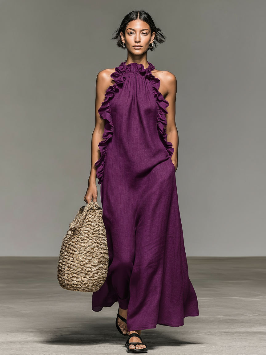 Purple - Model walking in a sleeveless, textured maxi dress with a ruffled halter neckline, carrying a woven straw bag.