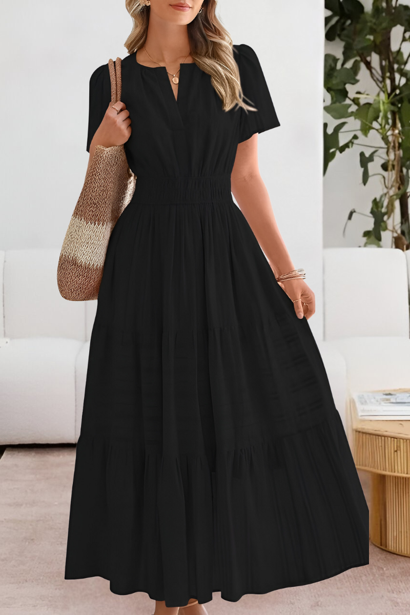 Black - A woman wearing a yellow textured cotton midi sundress with a smocked waist, split V-neckline, flutter sleeves, and a tiered skirt, holding a woven tote bag.