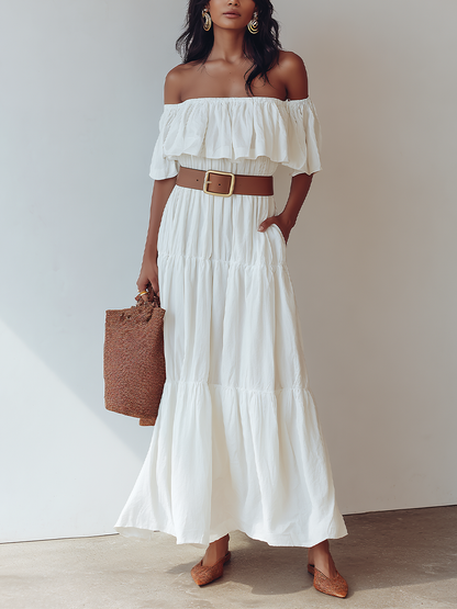 White - Woman wearing an off-the-shoulder tiered maxi dress with a ruffle neckline, styled with a wide belt and woven accessories.