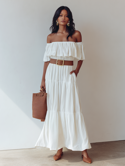 White - Woman wearing an off-the-shoulder tiered maxi dress with a ruffle neckline, styled with a wide belt and woven accessories.