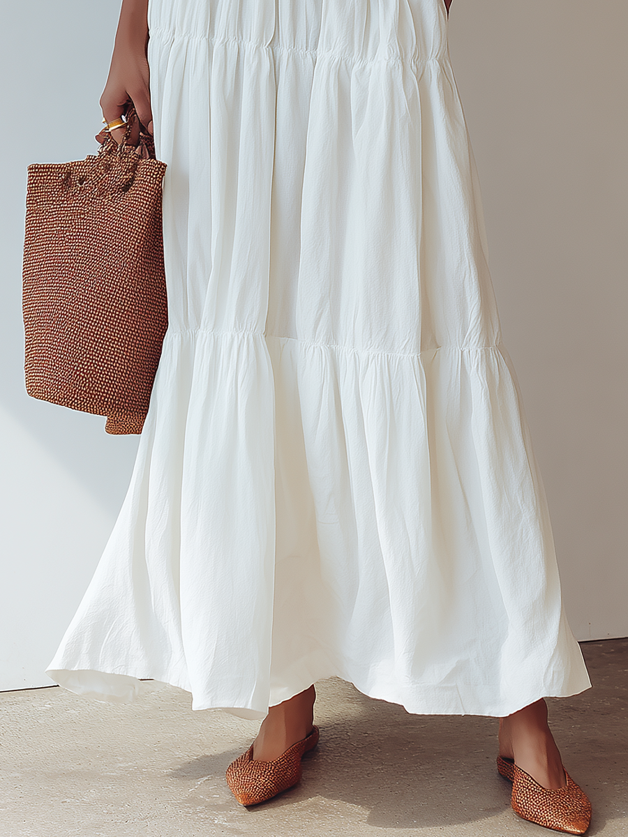 White - Woman wearing an off-the-shoulder tiered maxi dress with a ruffle neckline, styled with a wide belt and woven accessories.