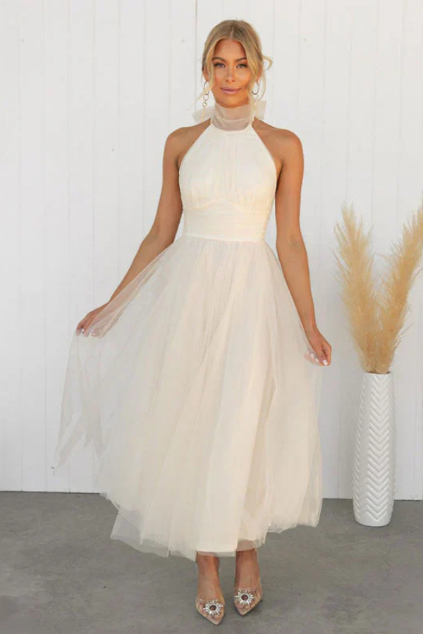Woman wearing a sleeveless tulle midi dress with a sheer halter neckline and structured corset bodice