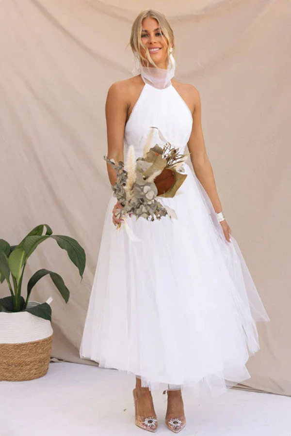 White - Woman wearing a sleeveless tulle midi dress with a sheer halter neckline and structured corset bodice