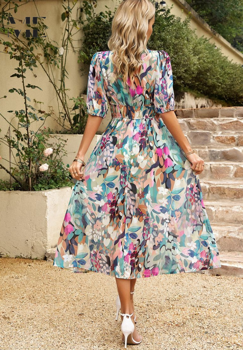 Light Blue - A woman wearing a vibrant, multicolored abstract floral print chiffon midi sundress with puff sleeves, a V-neckline, and a smocked waist, holding a woven straw clutch.