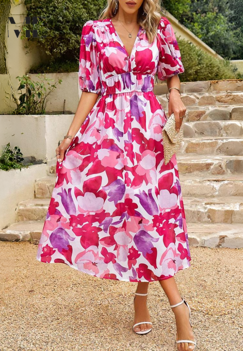 Blue - A woman wearing a vibrant, multicolored abstract floral print chiffon midi sundress with puff sleeves, a V-neckline, and a smocked waist, holding a woven straw clutch.