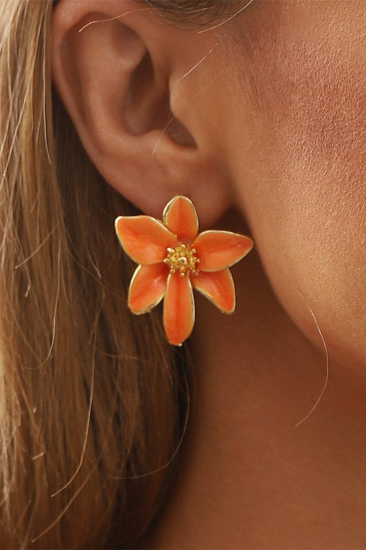 Close up of gold plated flower stud earrings with orange enamel petals