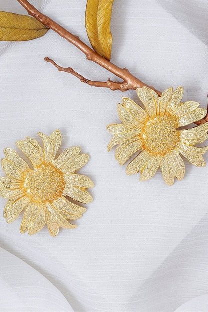 Close up of a large gold tone sunflower stud earring.