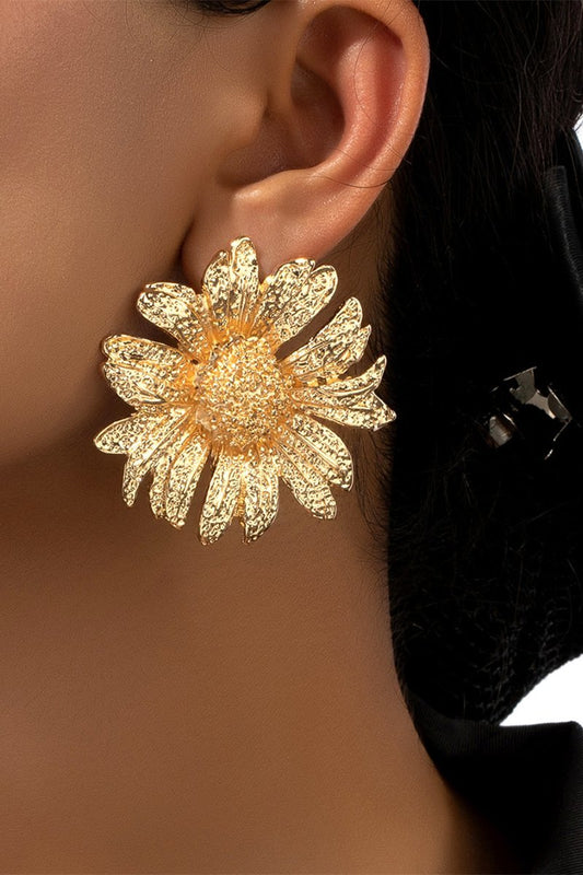 Close up of a large gold tone sunflower stud earring.