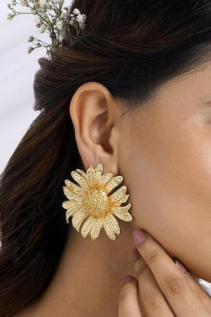 Close up of a large gold tone sunflower stud earring.