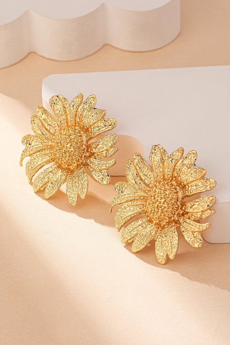 Close up of a large gold tone sunflower stud earring.