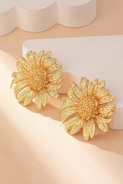 Close up of a large gold tone sunflower stud earring.