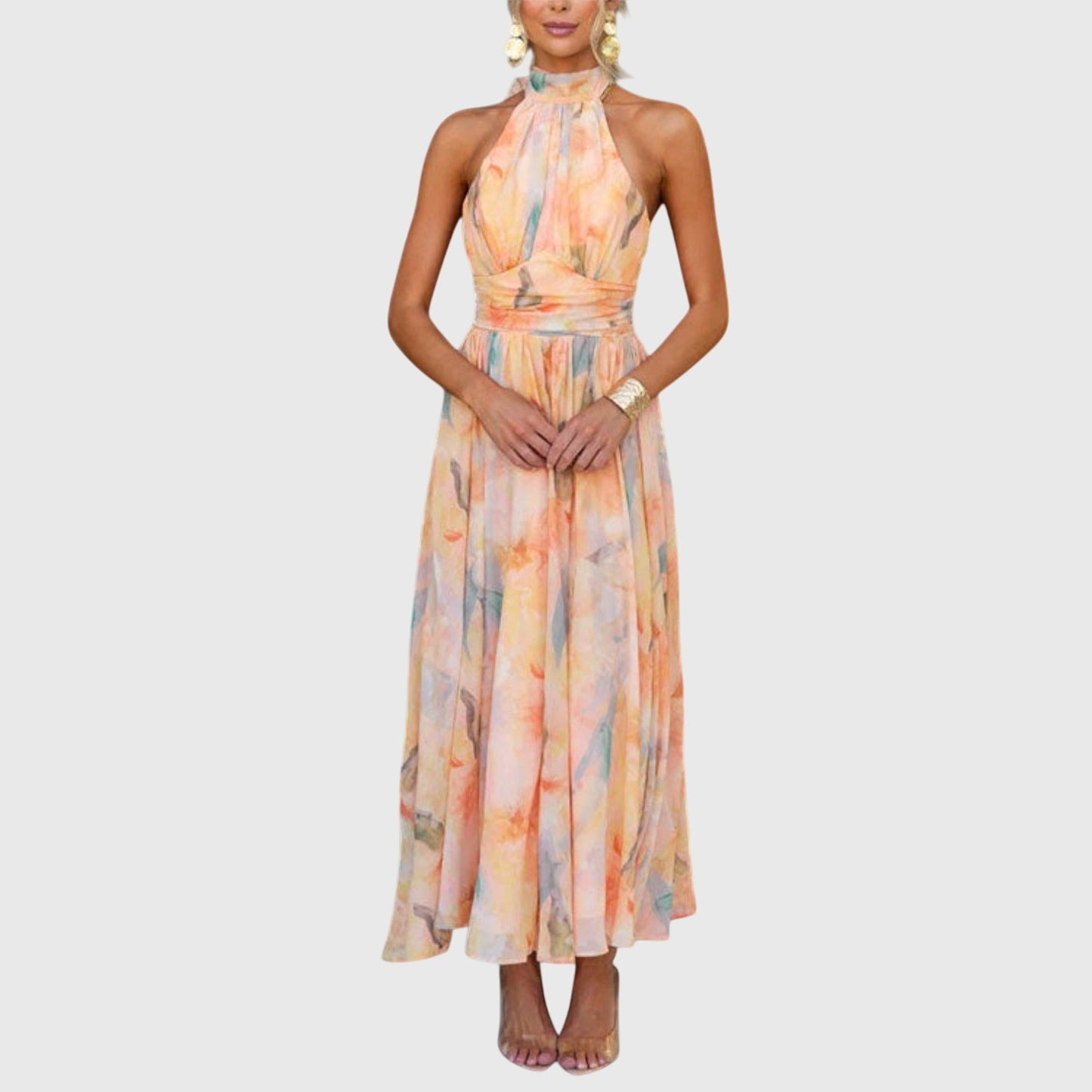 Premium - A woman wearing a sleeveless halter-neck maxi dress made of flowy watercolor chiffon in pastel orange, yellow, and blue shades, featuring a ruched waistband and a pleated A-line skirt.