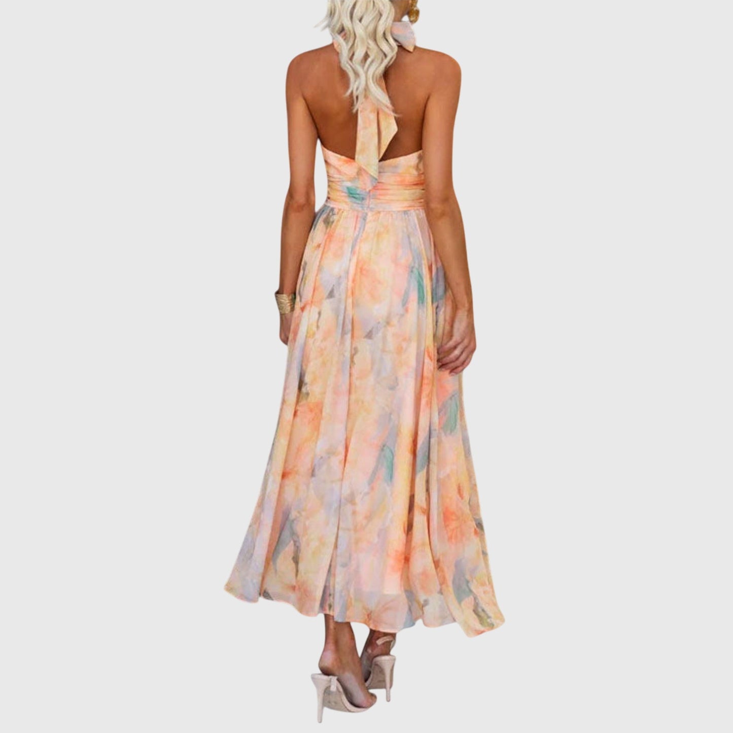 Premium - A woman wearing a sleeveless halter-neck maxi dress made of flowy watercolor chiffon in pastel orange, yellow, and blue shades, featuring a ruched waistband and a pleated A-line skirt.