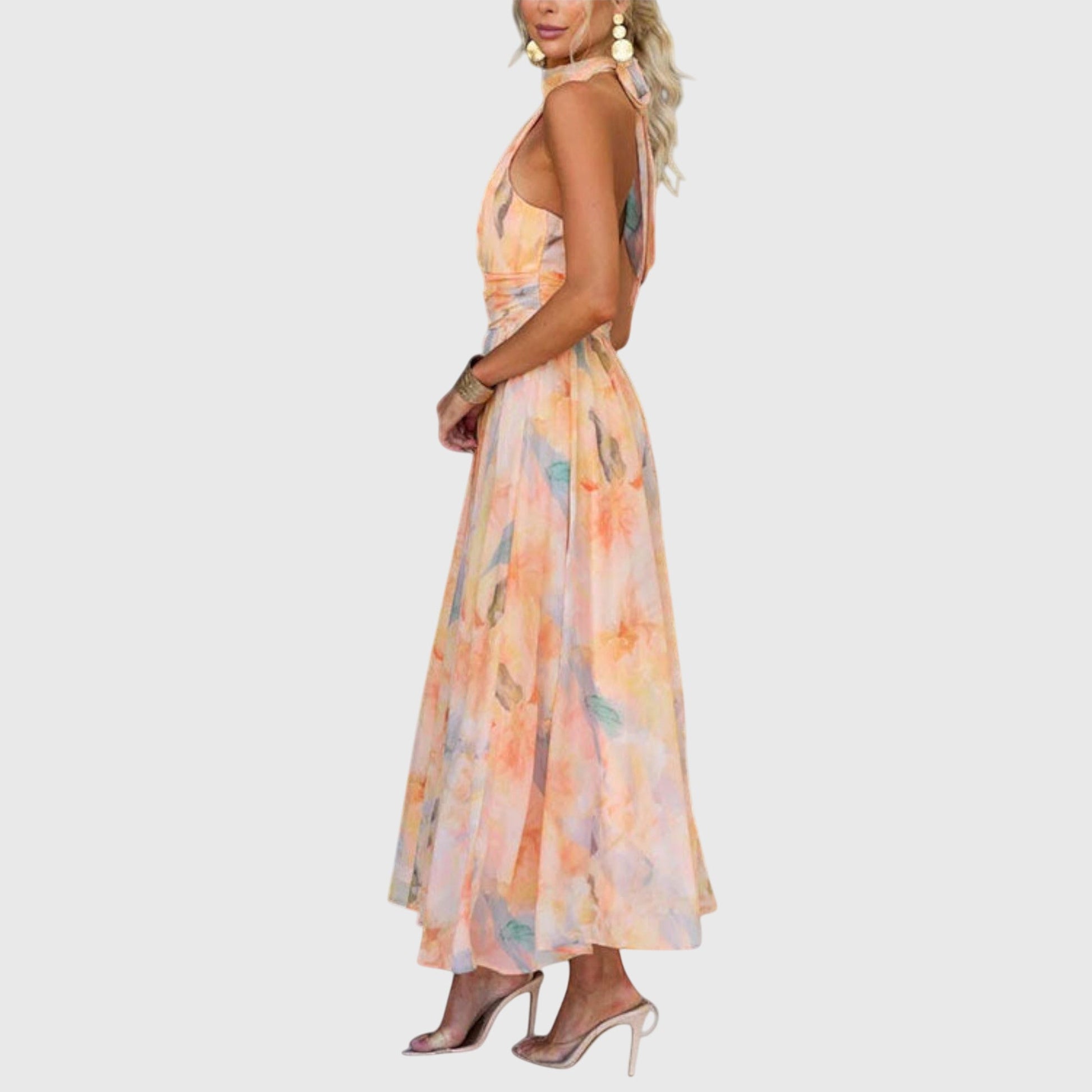 Premium - A woman wearing a sleeveless halter-neck maxi dress made of flowy watercolor chiffon in pastel orange, yellow, and blue shades, featuring a ruched waistband and a pleated A-line skirt.