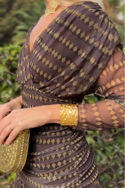 Woman in brown chiffon dress with gold accessories