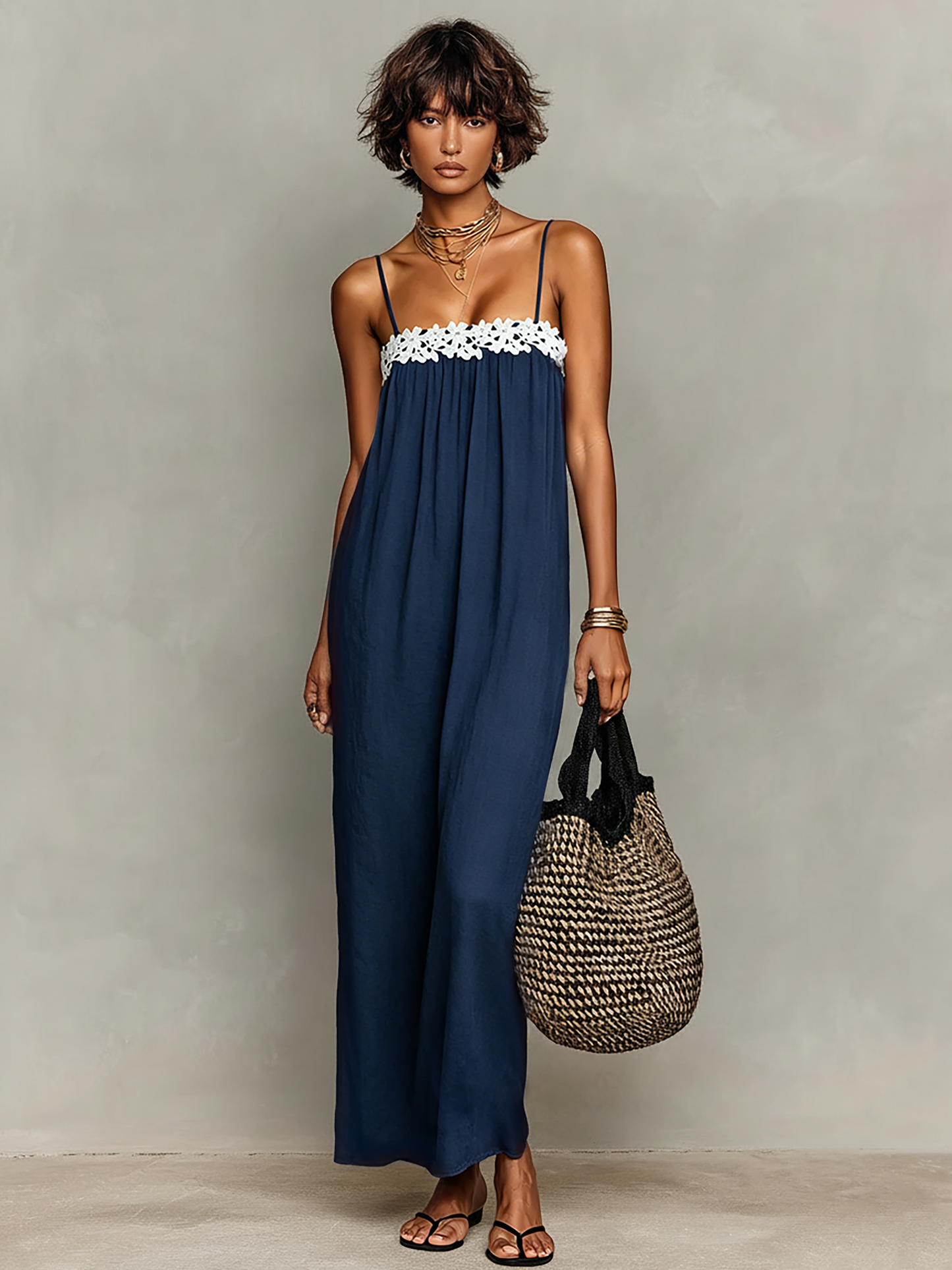 Navy - Model wearing a relaxed fit woven maxi dress featuring spaghetti straps and a crochet-trimmed straight neckline, styled with a woven tote bag and sandals.